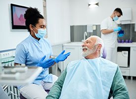 Dentist talking to smiling patient in treatment chair