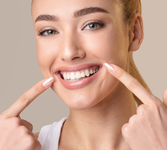 Woman pointing to her healthy smile after periodontal disease treatment