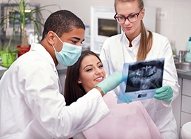 Dentist reviewing X-ray with smiling patient