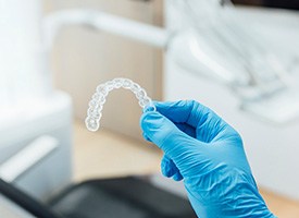 Dentist holding clear aligner with blue glove