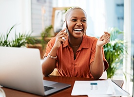 Woman smiling while talking on cell phone at home