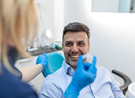 Patient smiling at dentist holding clear aligner