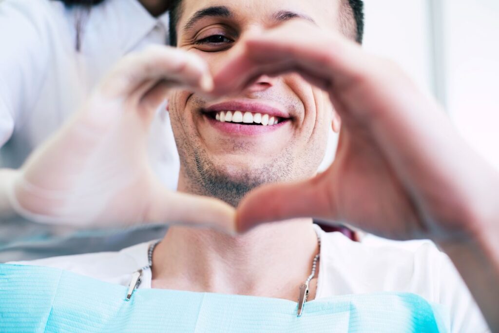 A man smiling in a dentists chair after a smile makeover.