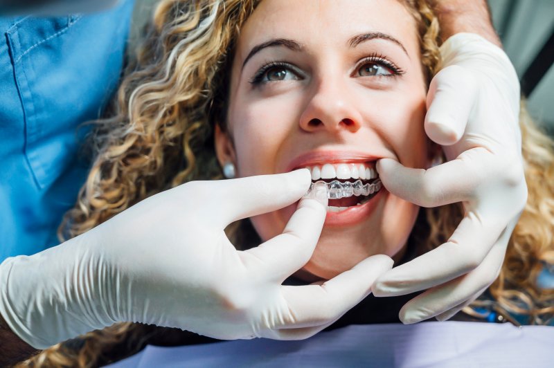 A dentist placing Invisalign trays over a patient’s teeth